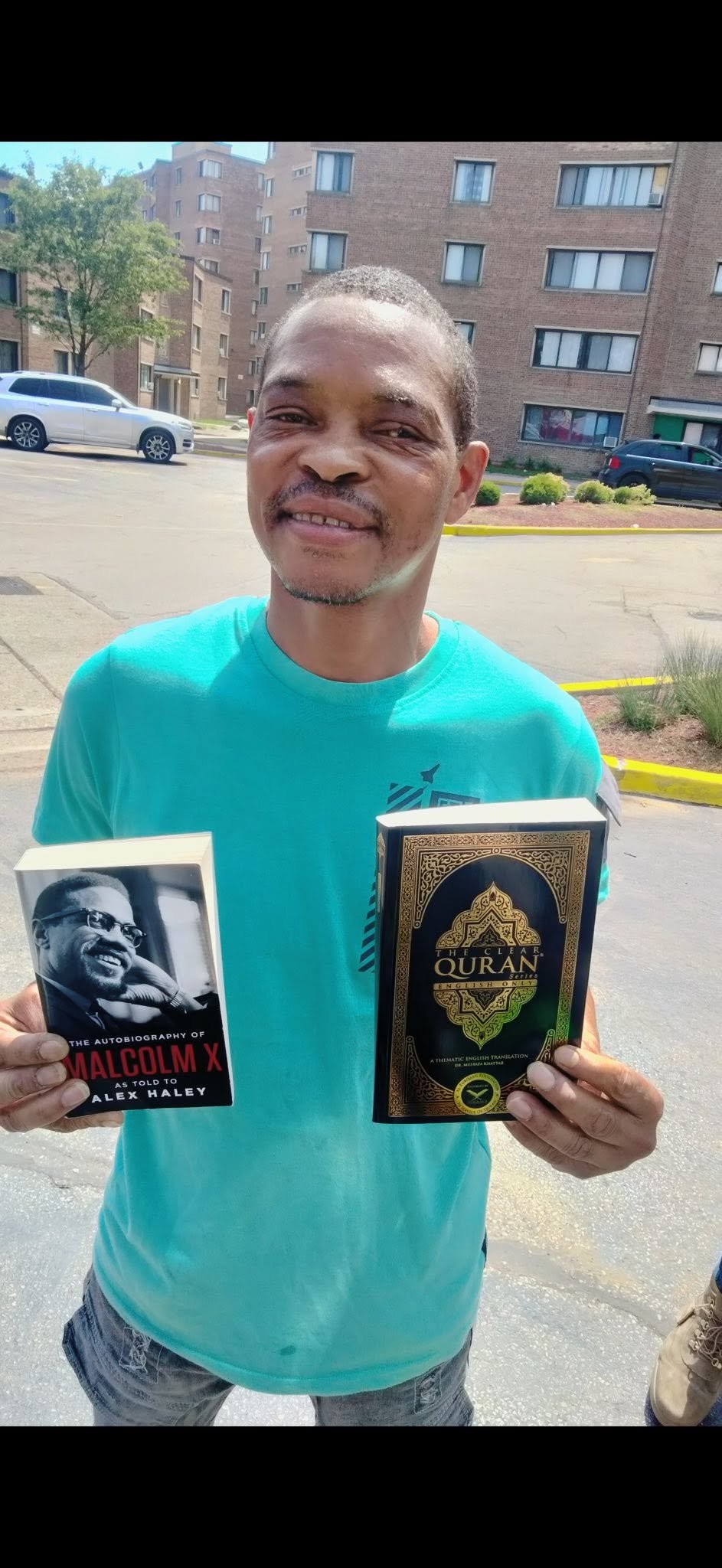 A young woman holding The Autobiography of Malcolm X and The Clear Qur'an